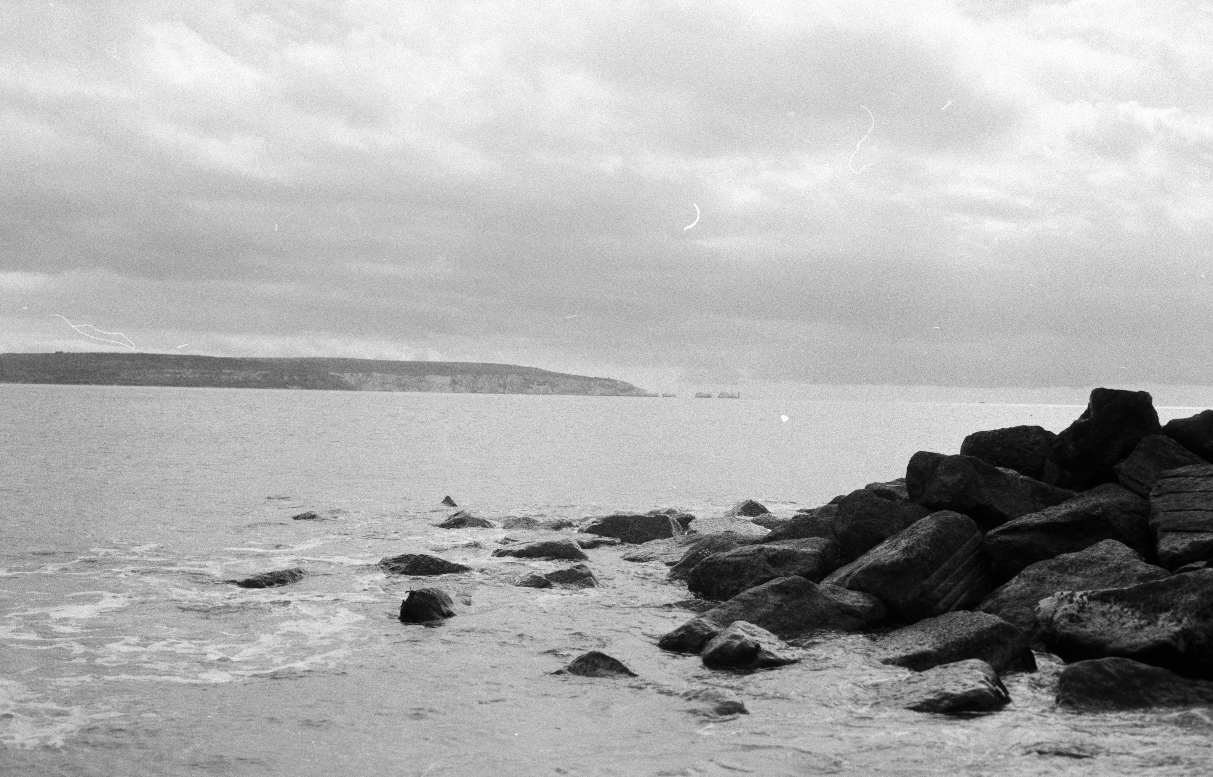 grayscale photo of rocks on beach